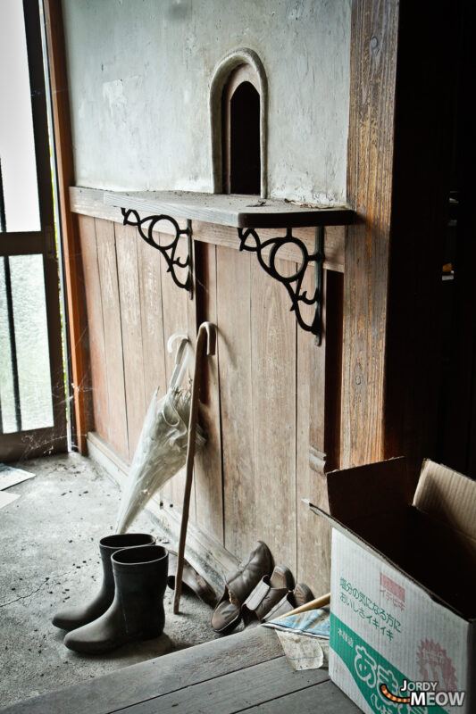 Rope hanging above rubber boots in a dusty abandoned hospital room, urban exploration scene.