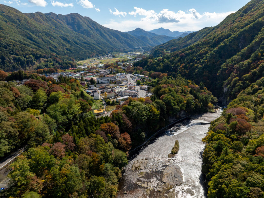Panoramic view of Japan’s Fukiware Falls river rapids winding through autumn forest valley