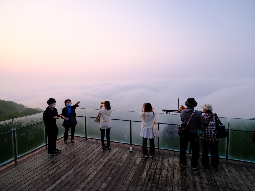 Visitors on Unkai Terrace observation deck at sunrise overlooking a sea of clouds