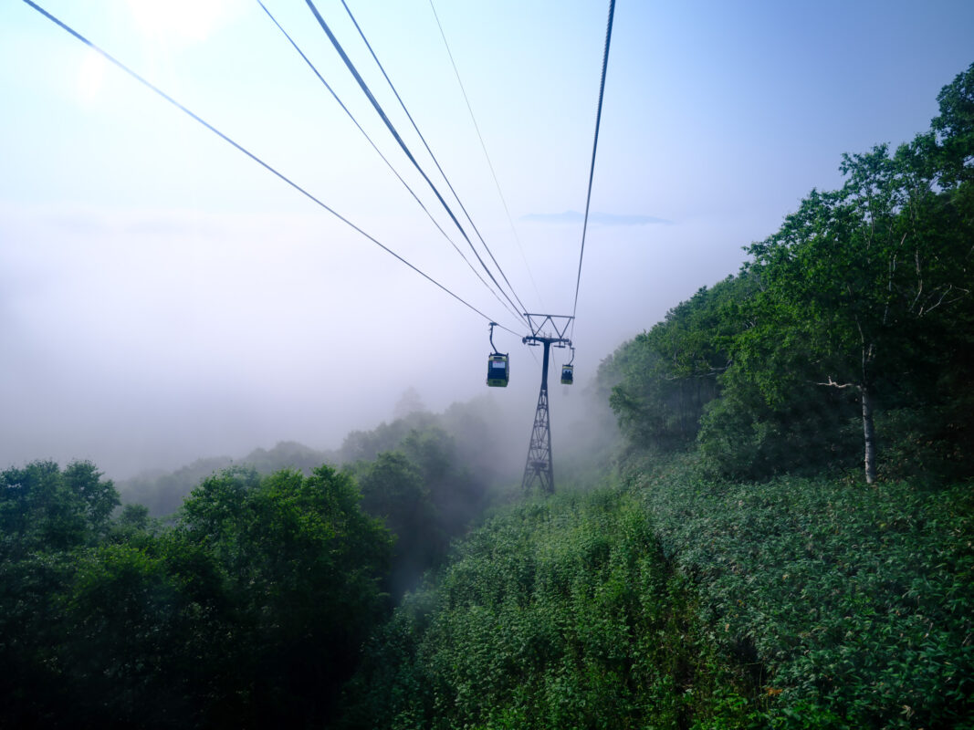 Unkai Terrace cable cars above Hokkaido mountains and sea of clouds in morning mist.
