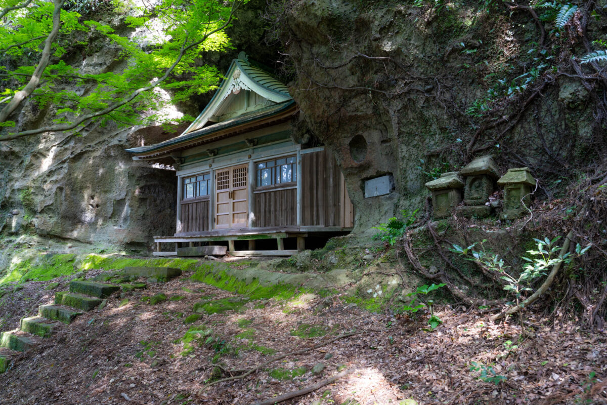 Kyu-Sento-ji cliffside Buddhist temple in forest, green-tiled roof and stone steps