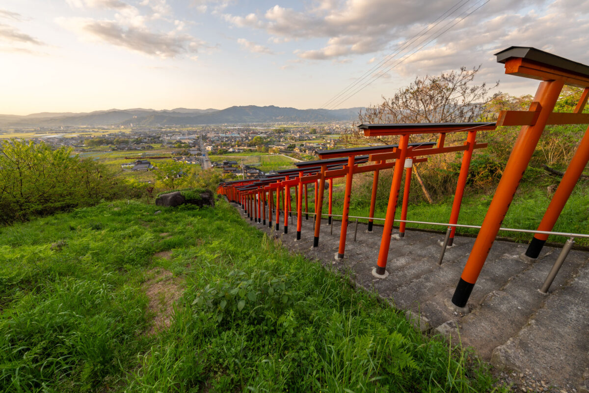 Vermilion torii gates at Ukiha Inari Shrine overlooking a valley town in Japan