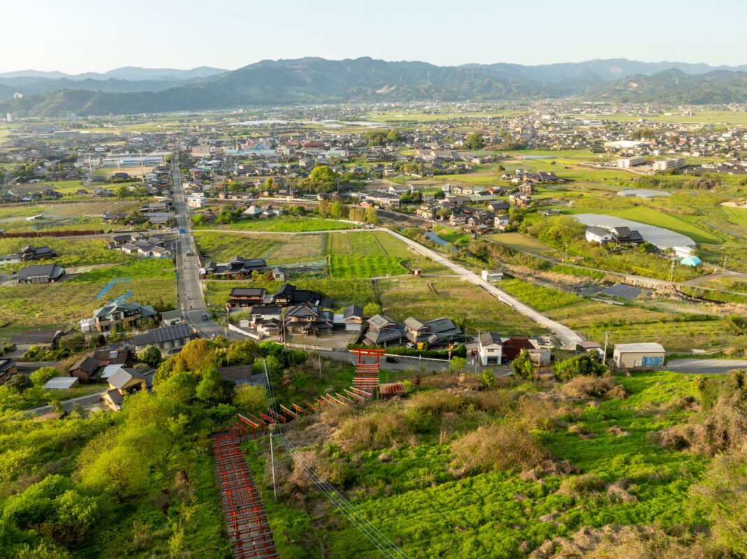 Ukiha Inari Shrine red torii gates overlooking rural valley farmland and distant mountains
