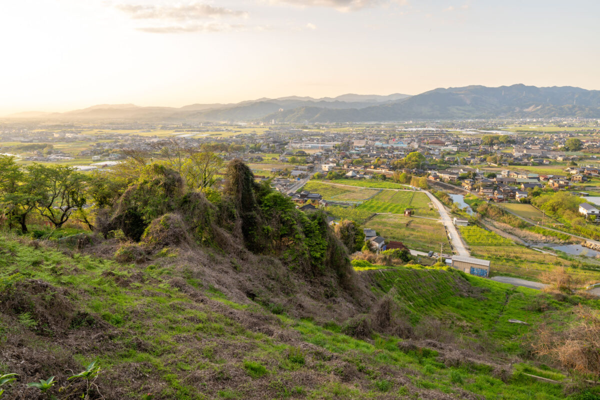 Ukiha Inari Shrine overlook of rural Japan valley, fields, river, and mountains at sunset.