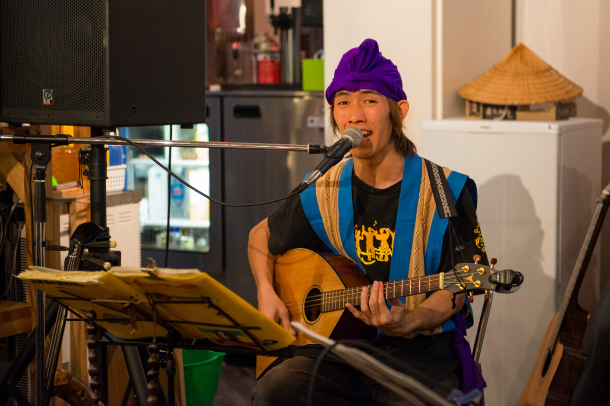 Musician sings and plays acoustic guitar in a cozy Miyako Island venue.