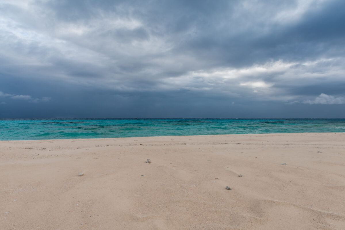 Empty Kumejima beach with turquoise sea and dramatic storm clouds over Okinawa