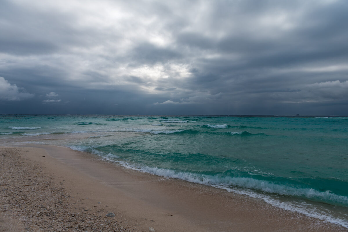 Storm clouds over Kumejima beach with turquoise waves and foamy surf