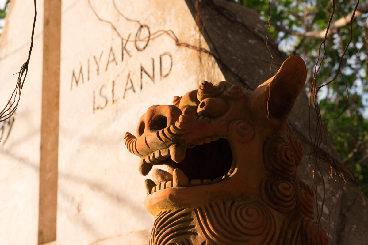 Shisa guardian statue by Miyako Island stone marker in Okinawa, Japan