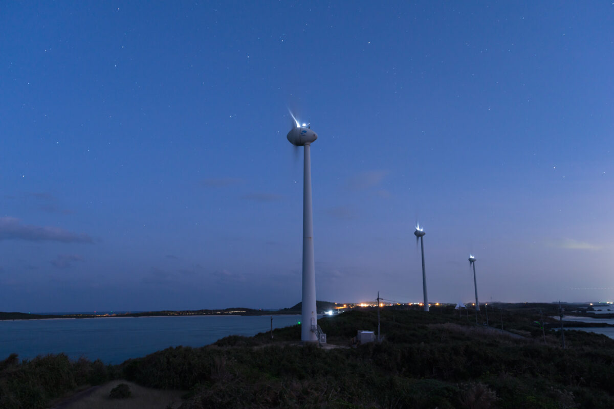 Wind turbines with red lights at twilight on Miyako Island, Okinawa coastline