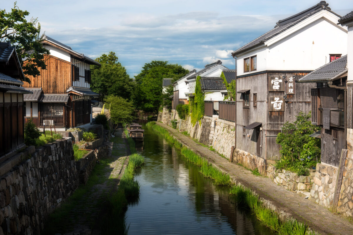 Omihachiman canal in Shiga, Japan, lined with historic merchant houses and greenery.