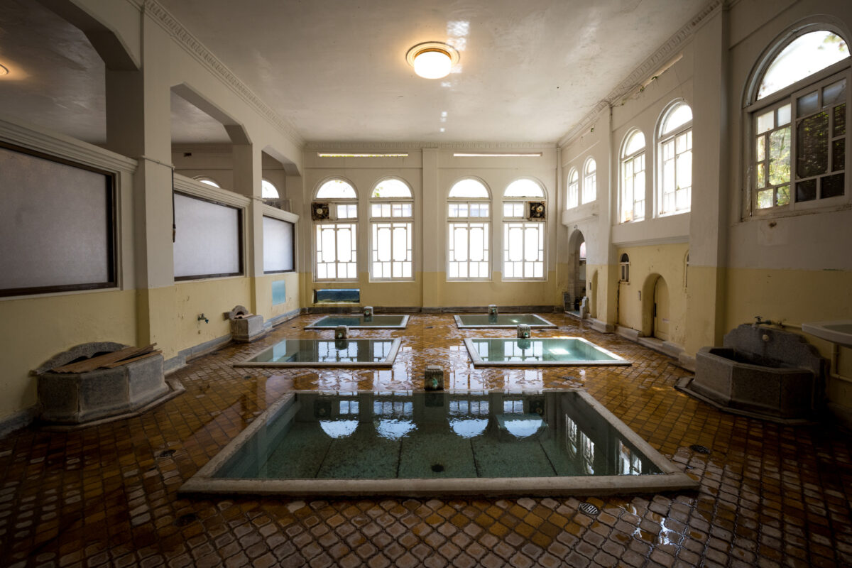 Historic Sekizenkan Ryokan onsen bath hall with rectangular hot spring pools and arched windows