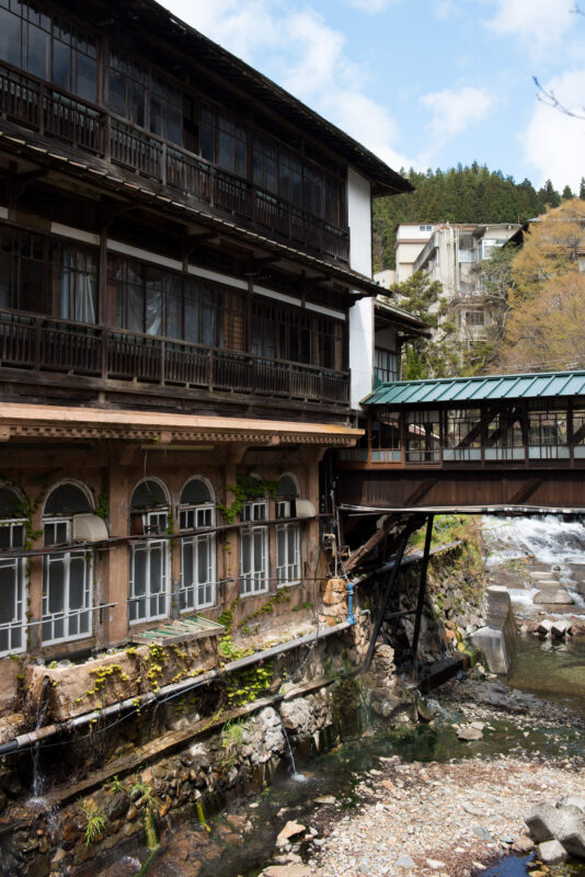 Historic Sekizenkan Ryokan beside mountain stream with covered wooden bridge in Japan