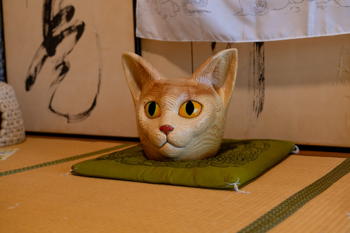 Cat head sculpture on green cushion on tatami in Japanese Zen temple interior