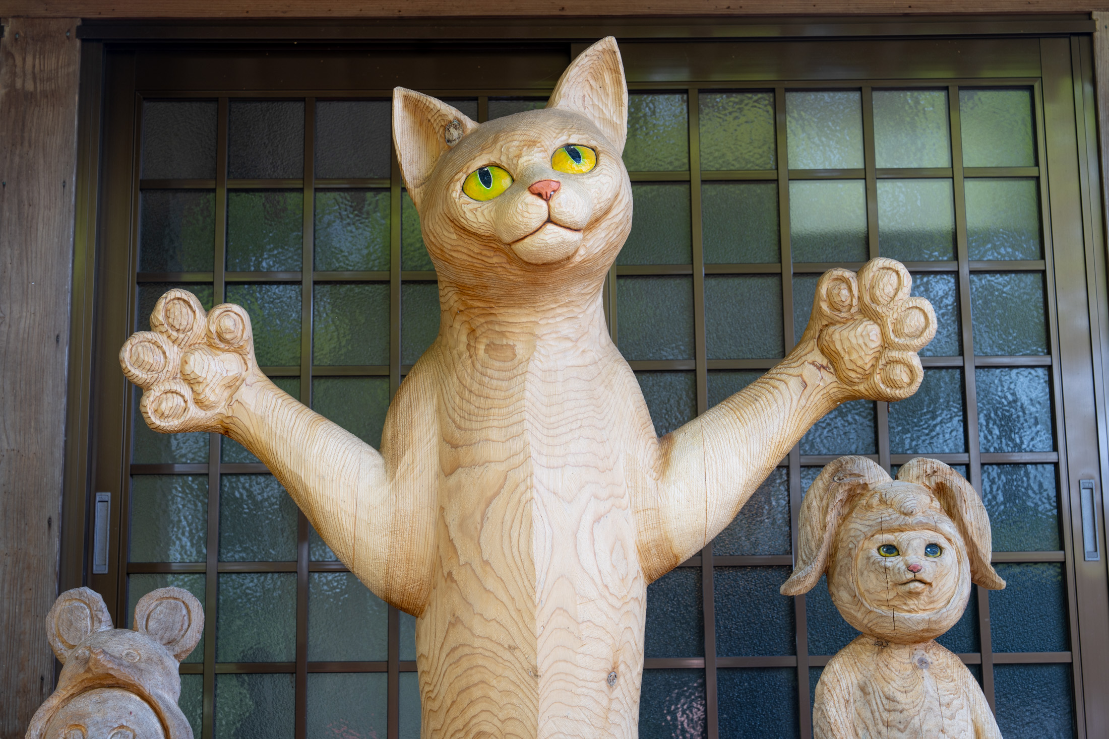 Wooden cat sculpture with raised paws at Unrin-ji Temple entrance in Japan