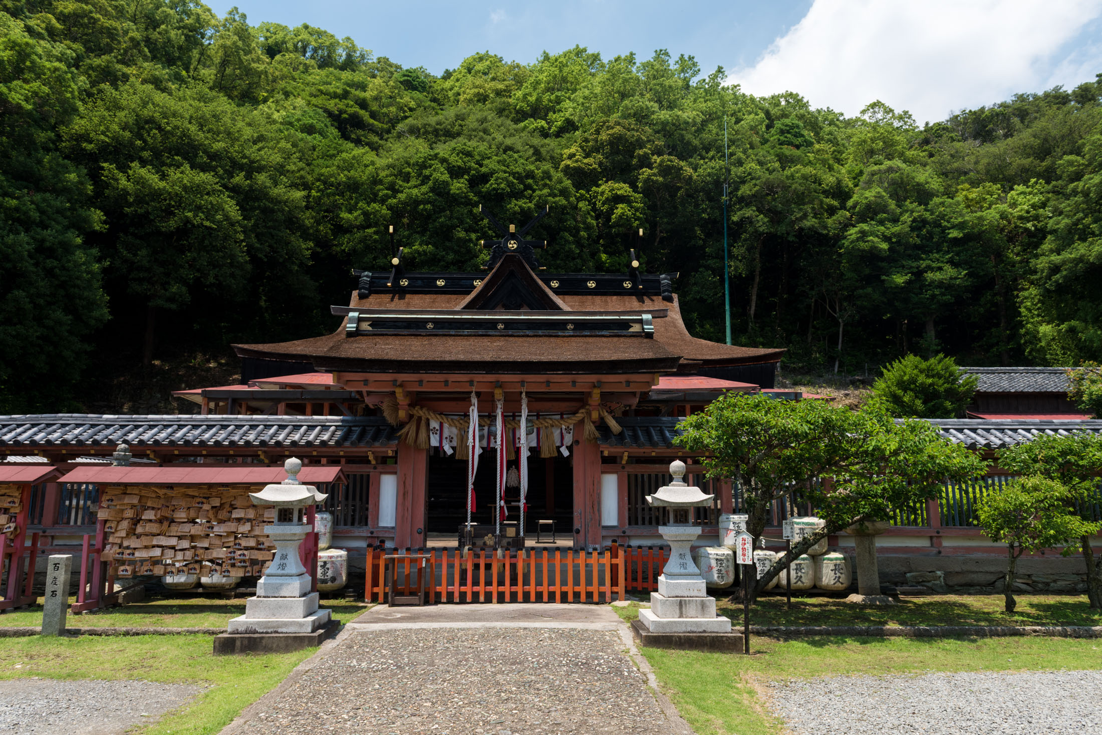 Stone path to Wakaura Tenmangu Shrine in Wakayama, Japan, with lanterns and forest backdrop.