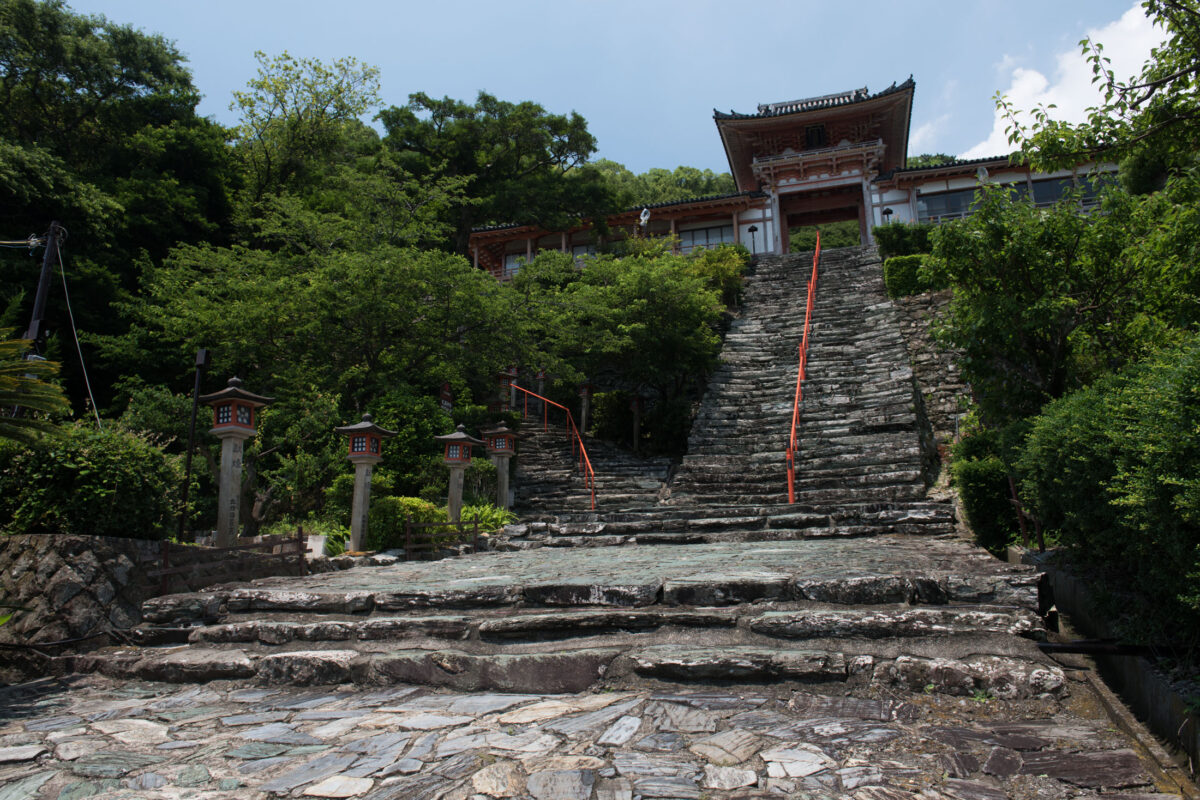 Steep stone staircase with red railings leading to Wakaura Tenmangu Shrine, Wakayama Japan.