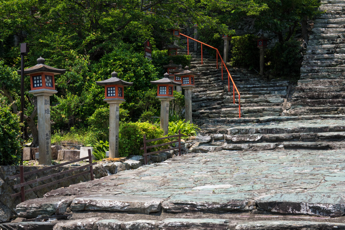 Stone path with lanterns and stairway at Wakaura Tenmangu Shrine, Wakayama, Japan.