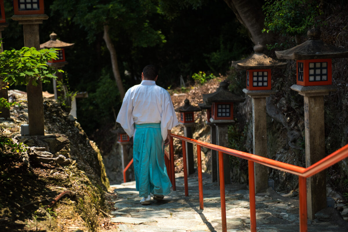 Shrine attendant descends stone steps at Wakaura Tenmangu Shrine, Wakayama, Japan