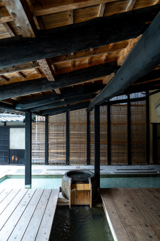 Tranquil Japanese wooden architecture interior with water basin fountain and slatted screens.